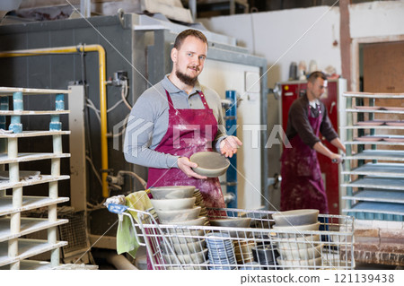 Young man posing with ceramic dishes Young man posing with ceramic dishes 121139438