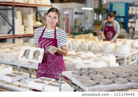 Young woman showing poured clay molds 121139448