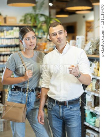 Couple exploring with interest shelves at organic foods store Couple exploring with interest shelves at organic foods store 121139470