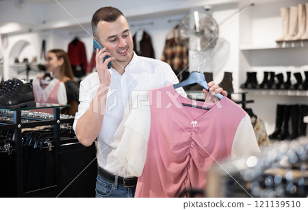 Young man chooses blouse and talks on phone 121139510