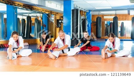Women with coach doing stretching before karate training 121139649