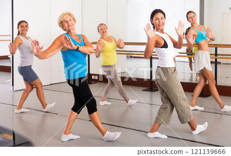 Group of active women practicing energetic dance in a studio 121139666