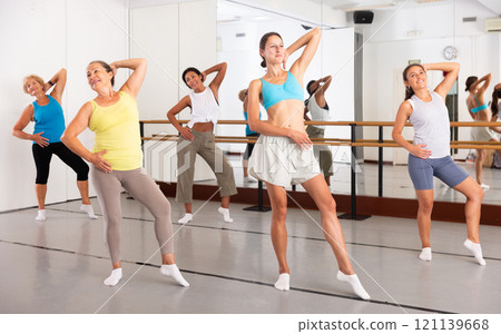 Group of active women practicing energetic dance in a studio 121139668