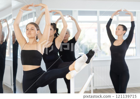Students of dance studio perform exercises under supervision of middle-aged female coach. 121139715