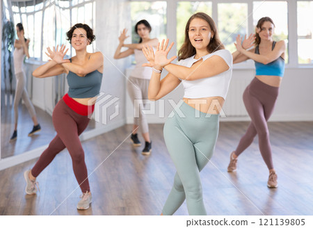 Cheerful young female instructor leading Zumba class for women Cheerful young female instructor leading Zumba class for women 121139805