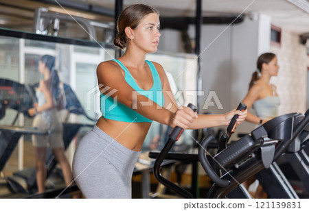 Young woman working out on elliptical machine Young woman working out on elliptical machine 121139831