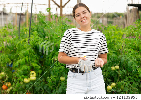 Young woman gardener standing in her farm smiling Young woman gardener standing in her farm smiling 121139955
