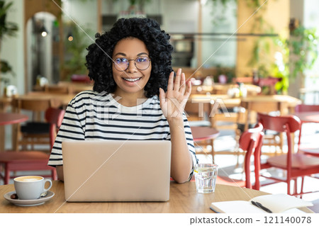 Dark-skinned woman in eyeglasses with a laptop in a cafe Dark-skinned woman in eyeglasses with a laptop in a cafe 121140078