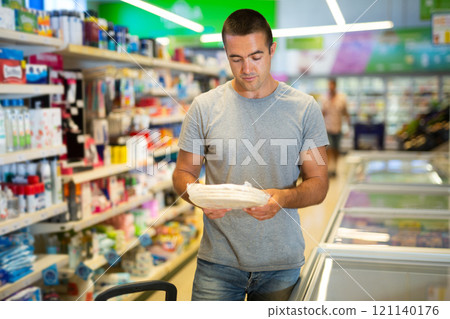 Interested man choosing frozen pizza base in supermarket 121140176