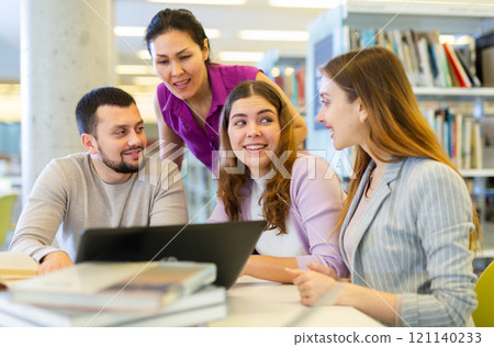 Group of students in the library is preparing for classes on a laptop Group of students in the library is preparing for classes on a laptop 121140233