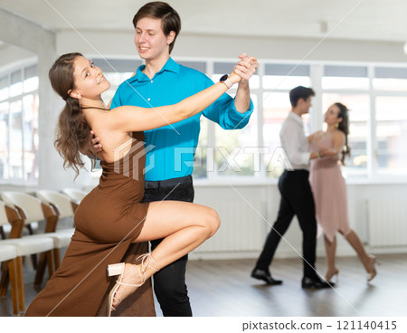 Couple in evening dresses enjoys pair dance tango, interacting with each other on floor 121140415