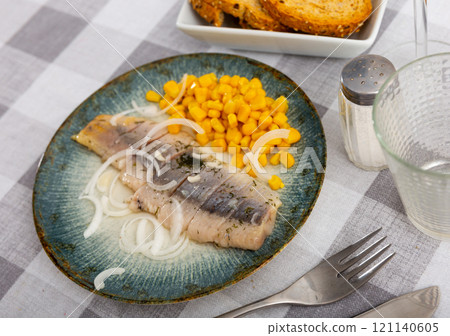 Slices of spicy marinated herring fillet with corn and onion Slices of spicy marinated herring fillet with corn and onion 121140605