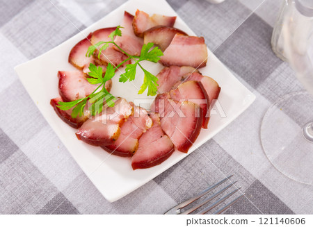 Slices of slightly spicy smoked pork bacon on plate with greens 121140606