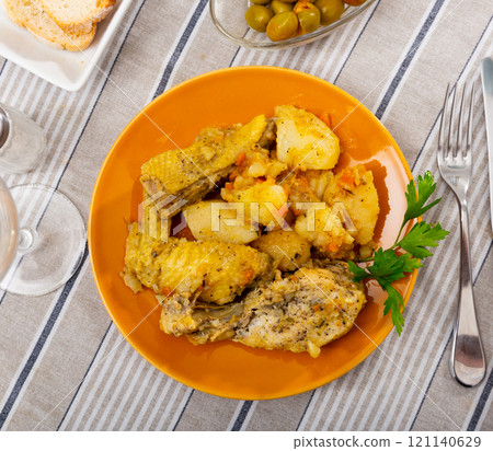 Baked chicken drumsticks and potatoes at plate closeup 121140629
