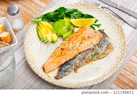 Fresh portion of roasted trout with avocado 121140651