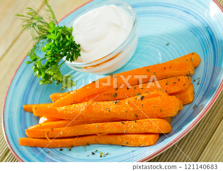 Vegetarian dish, fried carrot sticks served at plate with sour cream 121140683