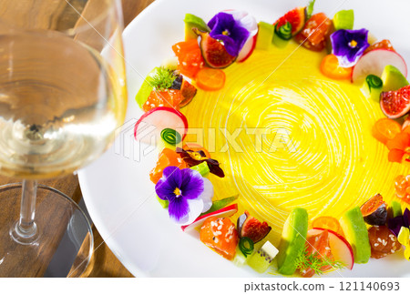Delicious ring from tartare salmon with avocado and vegetables, served with flowers 121140693