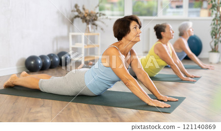 Mature lady performs asana pose dog muzzle up, Urdhva Mukha Shvanasana Mature lady performs asana pose dog muzzle up, Urdhva Mukha Shvanasana 121140869