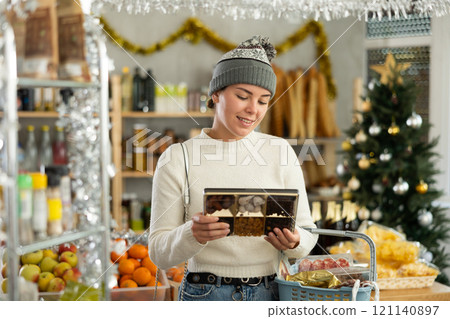 Smiling girl choosing dried fruits in Christmas decorated grocery store 121140897