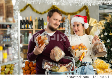 Happy husband and wife choose and buy nougat, panettone, marzipan, panellets together in grocery department of supermarket Happy husband and wife choose and buy nougat, panettone, marzipan, panellets together in grocery department of supermarket 121140921
