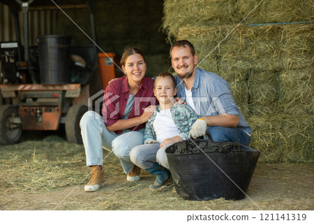 Portrait of happy family with son in backyard of horse farm, with hay in background Portrait of happy family with son in backyard of horse farm, with hay in background 121141319