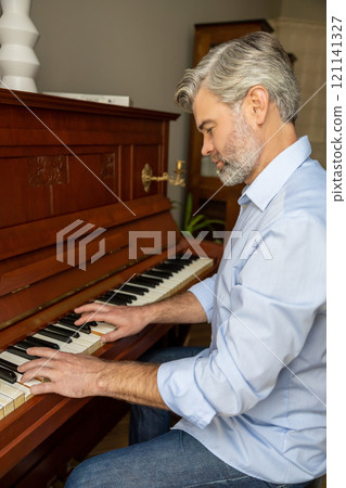 Gray-haired mature man playing the piano and looking involved Gray-haired mature man playing the piano and looking involved 121141327