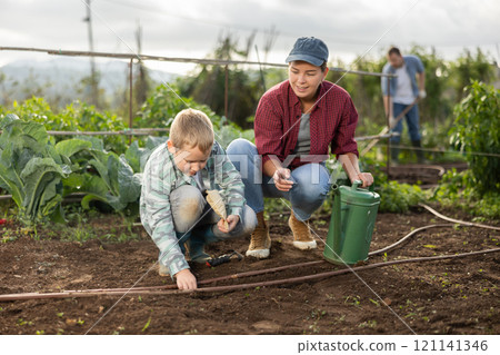 Woman and son planting seeds on farm 121141346