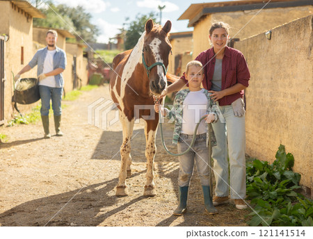 Woman and boy lead horse to feed 121141514