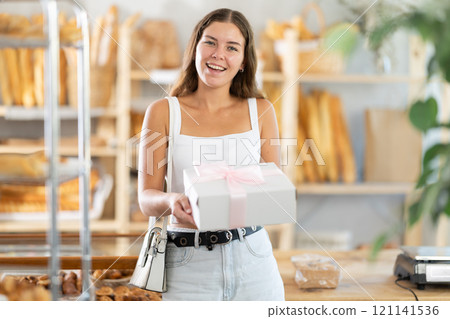 Young woman with pastries in box in bakery Young woman with pastries in box in bakery 121141536
