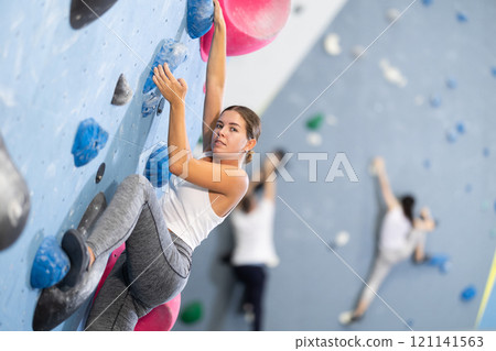 Young woman practicing rock climbing on climbing wall 121141563