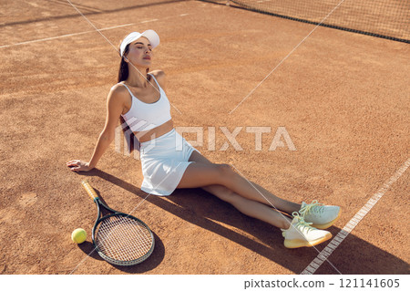 Female tennis player with a racket in hands resting on the tennis courts 121141605