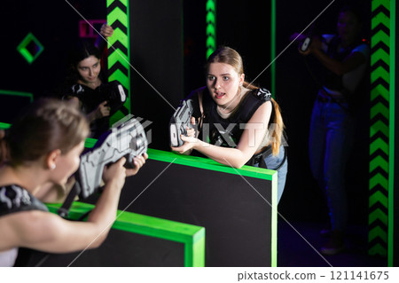 Girls play laser tag, jokingly fight with light weapons Girls play laser tag, jokingly fight with light weapons 121141675