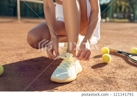 Close up of a female tying snickers on a tennis court Close up of a female tying snickers on a tennis court 121141791