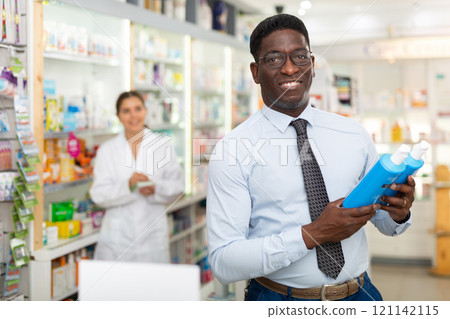 African american male chooses a therapeutic shampoo, to buy 121142115