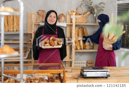 Hospitable saleswoman presenting traditional pastries in Muslim bakery Hospitable saleswoman presenting traditional pastries in Muslim bakery 121142185