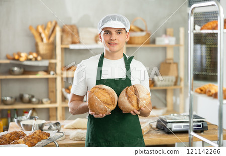 Bakery male employee holds ready made bread of bread in hands Bakery male employee holds ready made bread of bread in hands 121142266