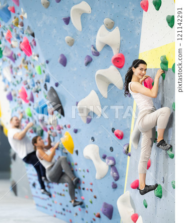 Young woman doing rock climbing on climbing wall 121142291