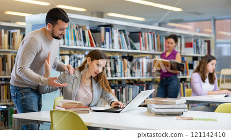 Woman gesturing to stop guy flirting with her in library Woman gesturing to stop guy flirting with her in library 121142410