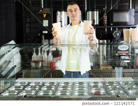 Young man holding out cups of bubble tea Young man holding out cups of bubble tea 121142571