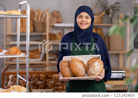 Asian Muslim woman bakery worker sells bread, stand at counter and wait for visitors 121142603
