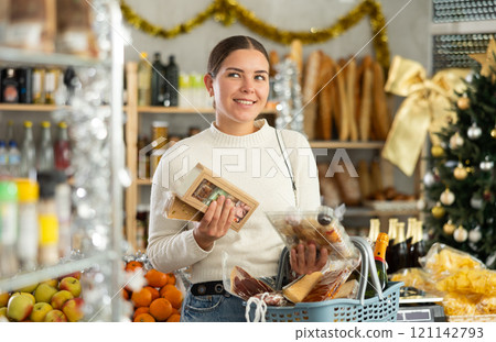 Girl shopper selects sweet nougat and panellets in grocery section of a supermarket for gifting and celebrating Christmas 121142793