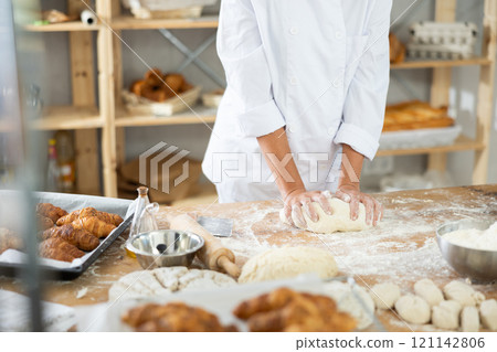 Female hands kneading dough on table, closeup 121142806