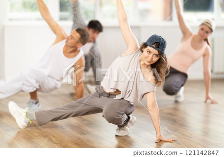 Girl and her students perform hip hop dance on one bent leg, movement in horizontal plane near floor Girl and her students perform hip hop dance on one bent leg, movement in horizontal plane near floor 121142847