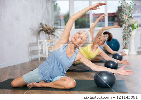 Group of elderly woman doing pilates with soft ball in studio 121143061