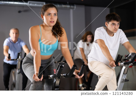 Young girl doing cardio workout on exercise bike in gym 121143280