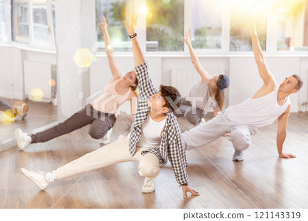 Man and his students perform hip hop dance on one bent leg, movement in horizontal plane near floor Man and his students perform hip hop dance on one bent leg, movement in horizontal plane near floor 121143319