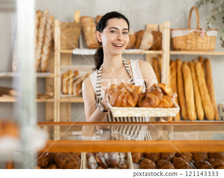 Young woman seller with basket of croissants 121143333