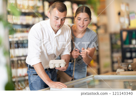 Man with package of eggs in hands talks with wife about buying ingredients for making homemade pie. 121143340
