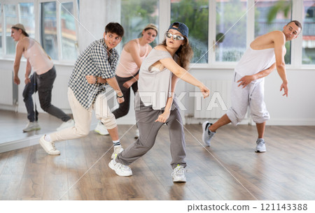 Young girl standing performs basic hip hop movements in front of group of students Young girl standing performs basic hip hop movements in front of group of students 121143388