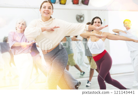 Cheerful girl enjoying active dancing during group training Cheerful girl enjoying active dancing during group training 121143441